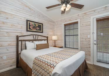 Bedroom with queen bed and ceiling fan in a two bedroom cabin at Piney Shores Resort in Conroe, Texas