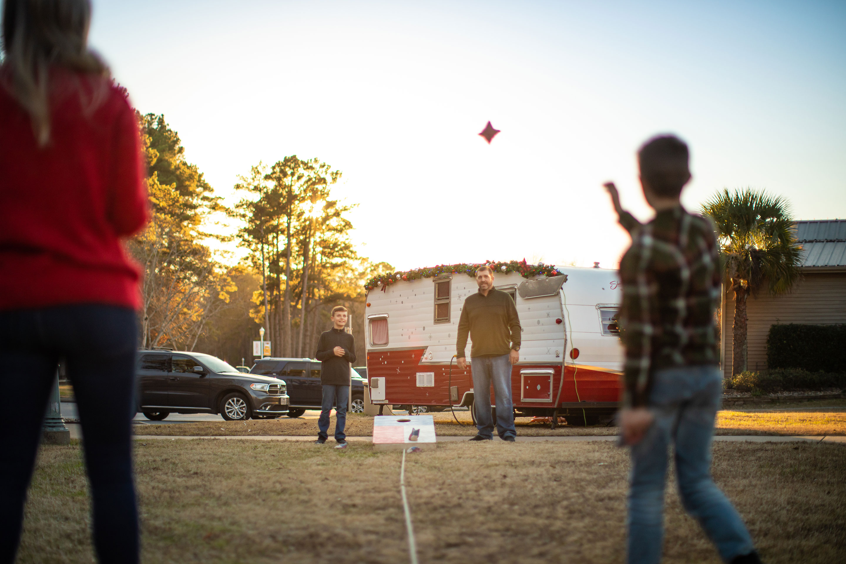 Author, Amanda Nall (left), plays cornhole with her family as the sun sets and they are surrounded with holiday-themed decorations.