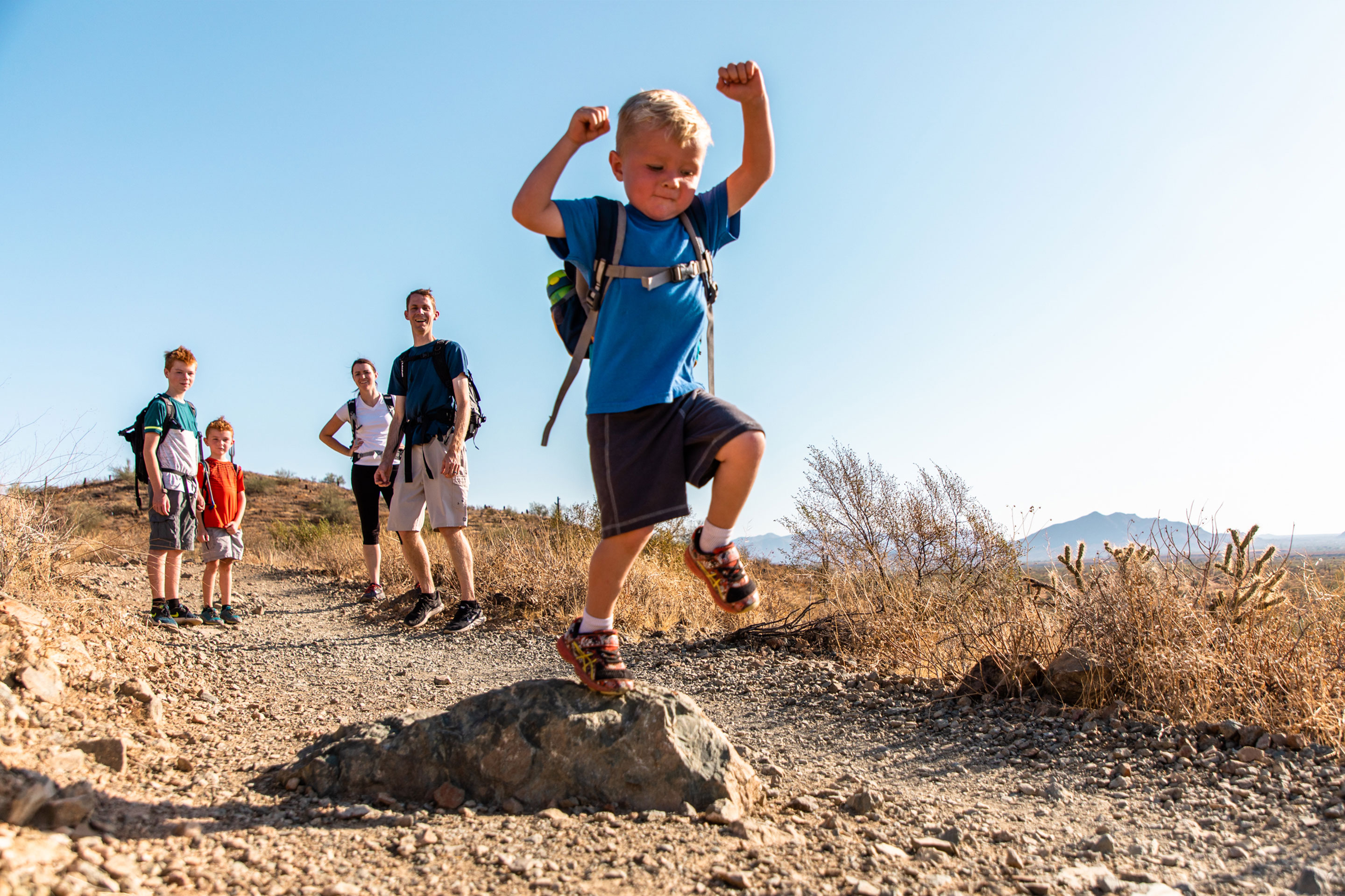 The Averett Family watches as their youngest member bounds over rocks on the trail at Papago Park.