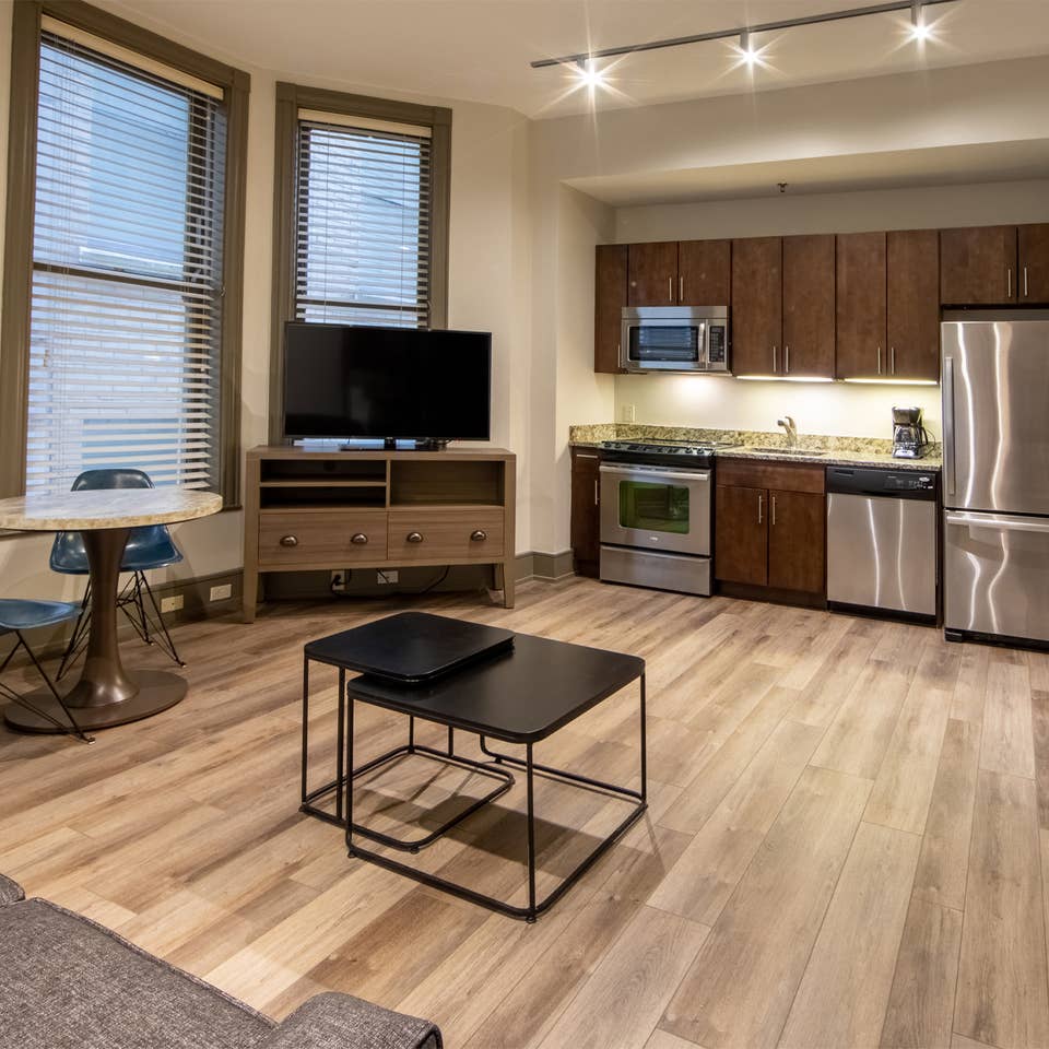 One bedroom villa living area with couch, three windows, TV and full kitchen at New Orleans Resort in Louisiana.