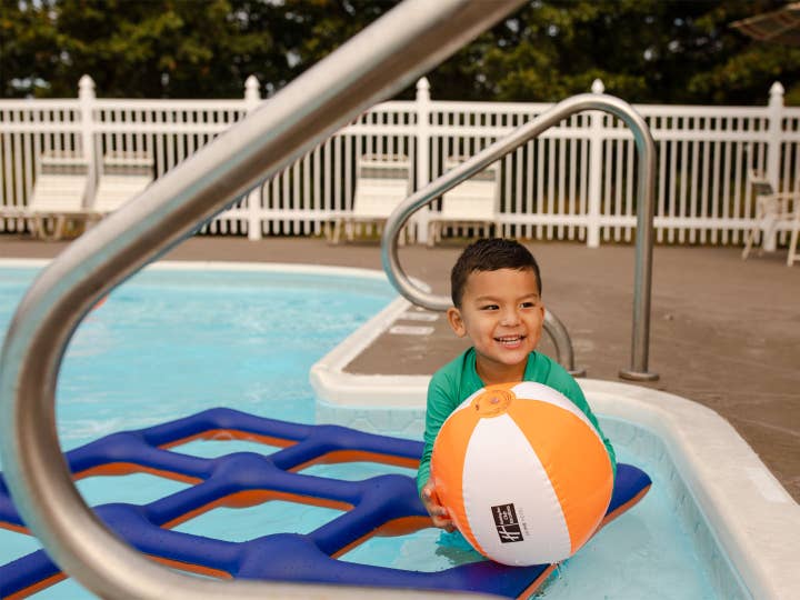 Young child playing with beach ball in outdoor pool at Holiday Hills Resort in Branson, Missouri.