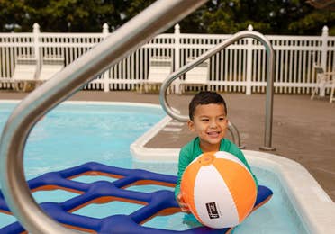 Young child playing with beach ball in outdoor pool at Holiday Hills Resort in Branson, Missouri.