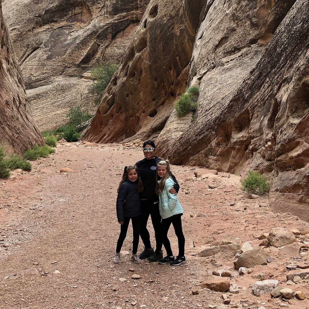 Chris (middle) stands with Kyndall (right) and Kyler (left) in front of rock formations at Capital Gorge.