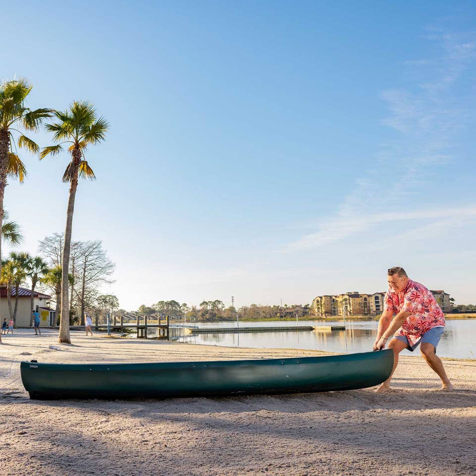 Man pulling a canoe into the water at Orange Lake Resort in Orlando, FL