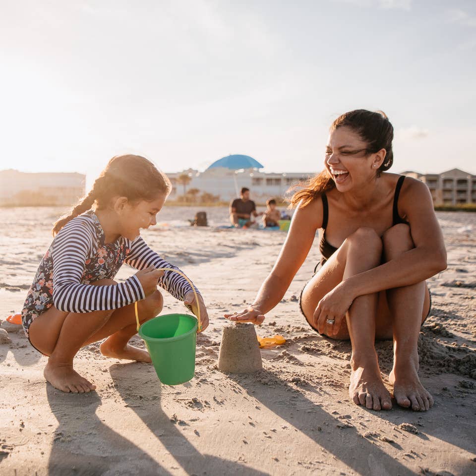 Mother and child playing in sand at Cape Canaveral Beach Resort in Florida.