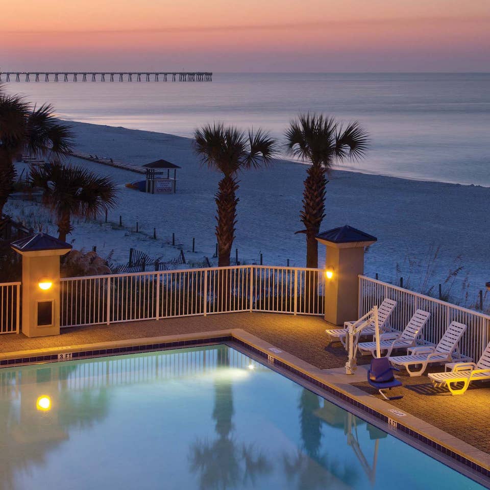 View of outdoor pool looking onto beach at sunset at Panama City Beach Resort in Florida.