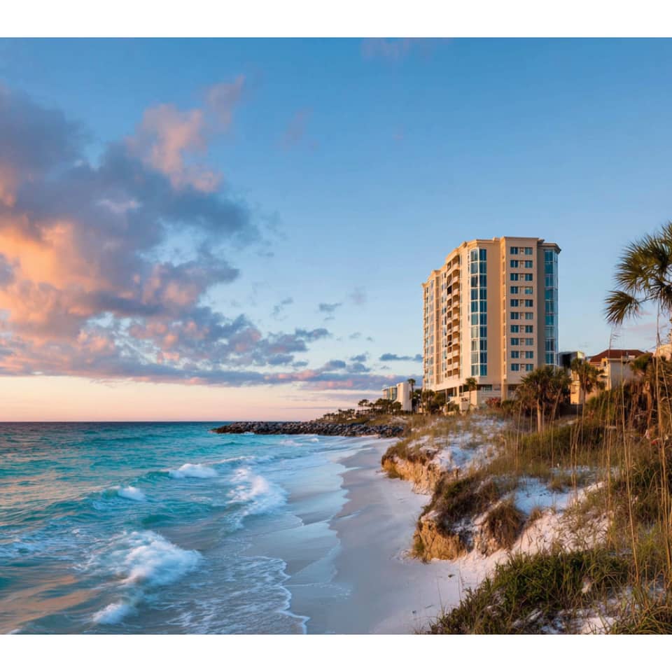 Clouds glowing pink float over rocky shoreline at sunset.