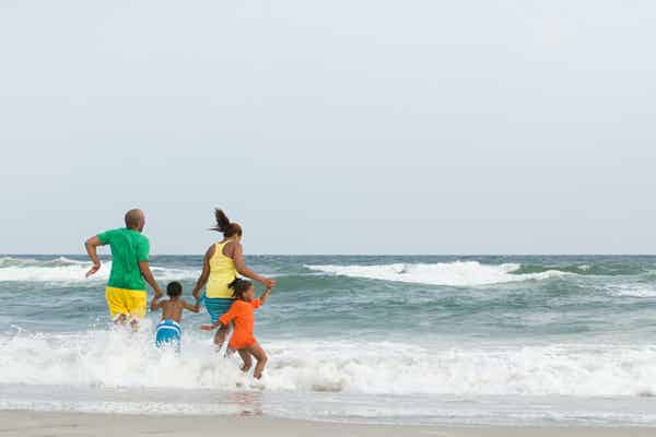 Family running into the waves at the beach.