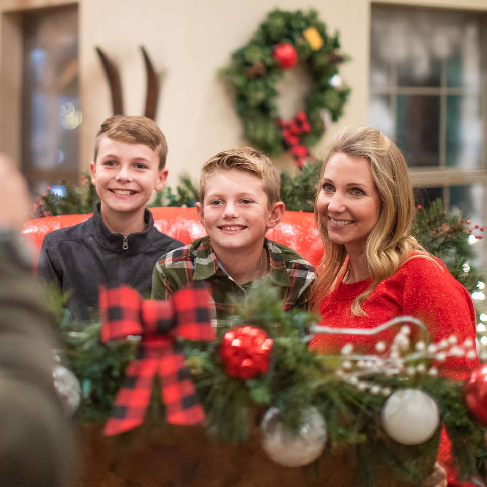 Author, Amanda Nall (right), pose on Santa's sleigh with her sons for a photograph surrounded by holiday decor.
