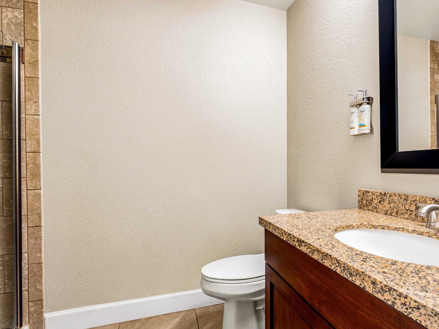 Granite vanity and tiled shower in a bright, modern bathroom.
