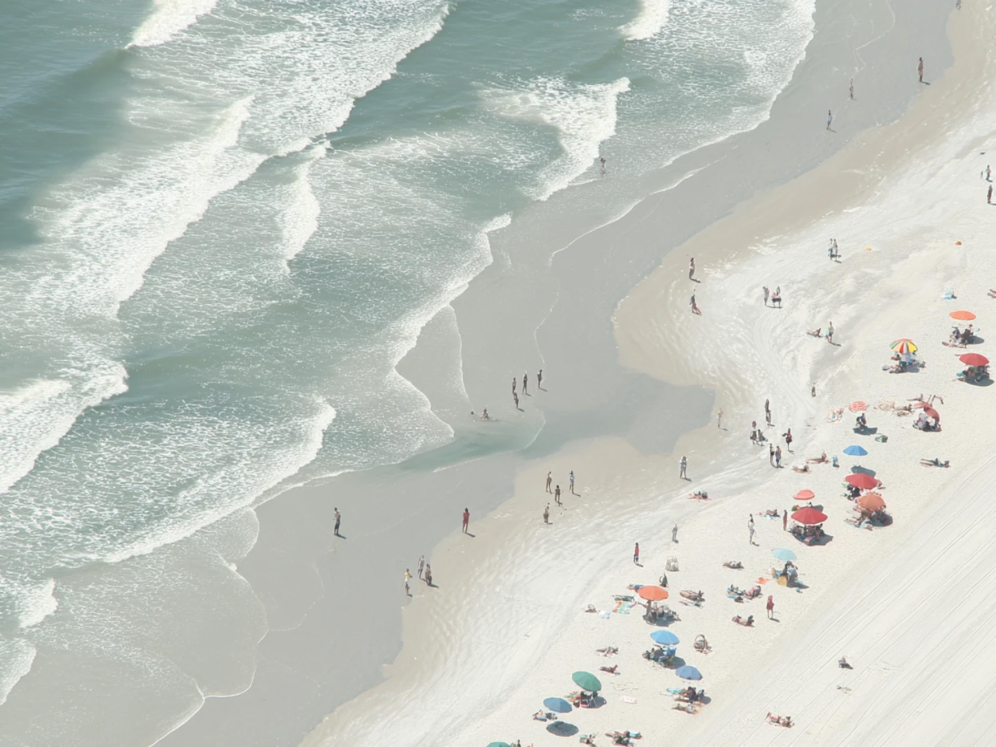 Aerial view of Dayton Beach, showing the ocean and people with umbrellas.