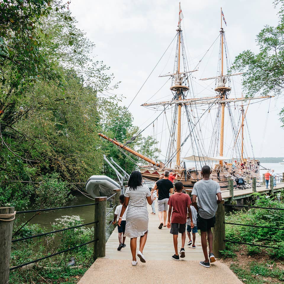 A family walks towards the Susan Constant ship at Jamestown Settlement in Williamsburg, Virginia.