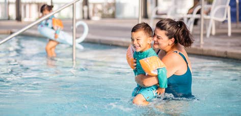 Adult holding child while laughing in resort pool at Holiday Hills Resort in Branson, Missouri.
