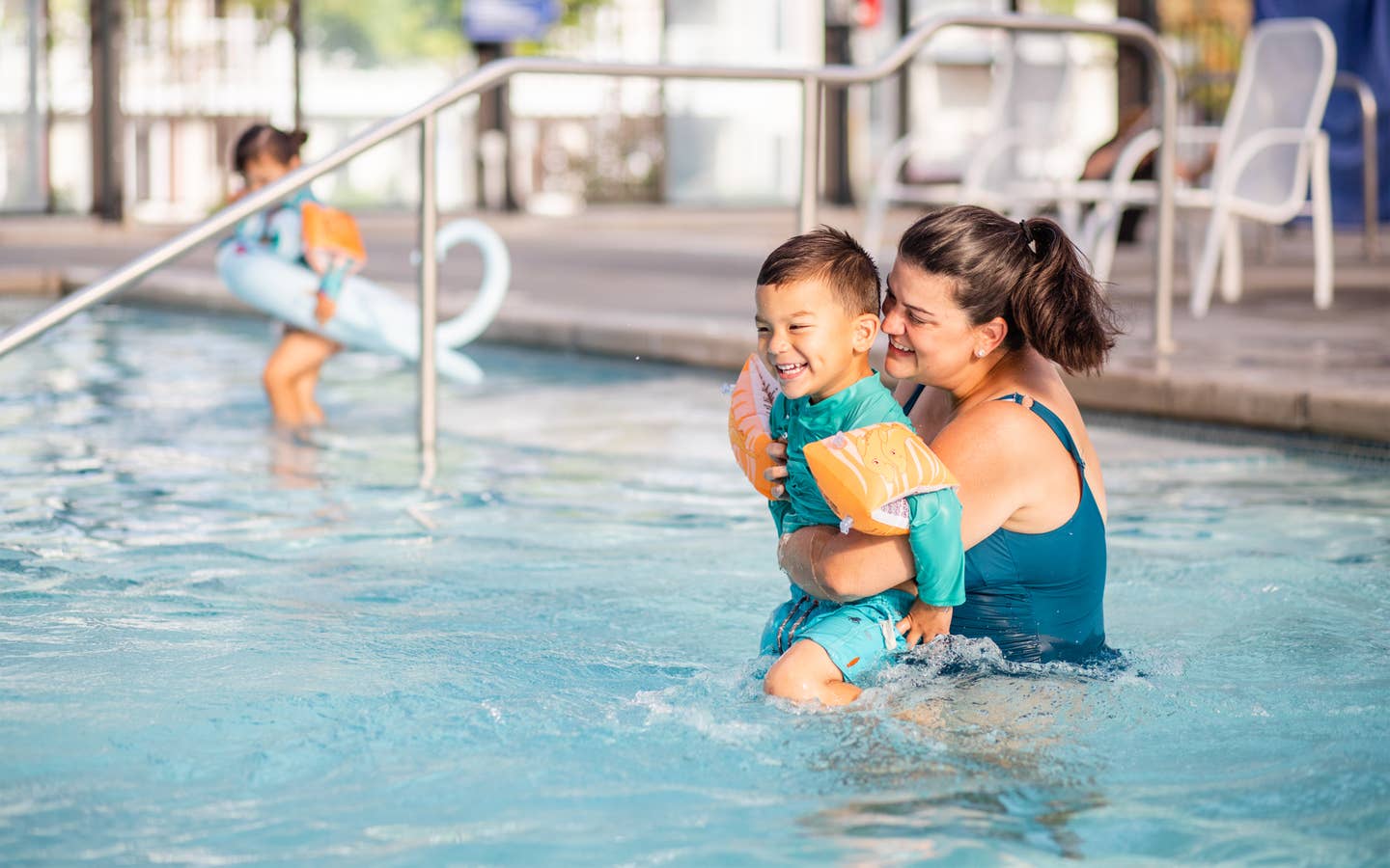 Adult holding child while laughing in resort pool at Holiday Hills Resort in Branson, Missouri.