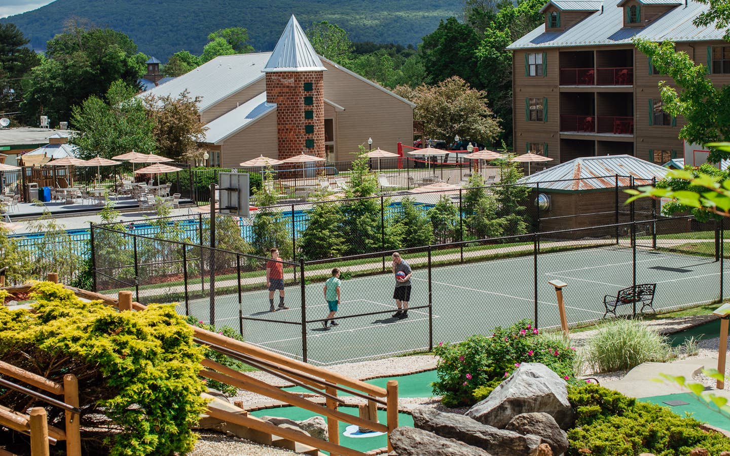 Family playing basketball on sports court at Oak n' Spruce Resort in South Lee, Massachusetts.