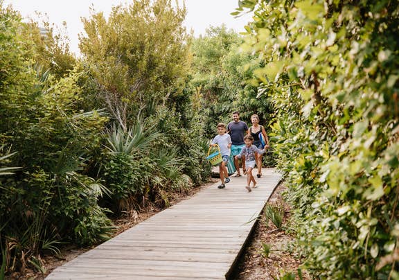 Family of four walking down walkway near Cape Canaveral Beach Resort in Florida.