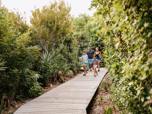 Family of four walking down walkway near Cape Canaveral Beach Resort in Florida.