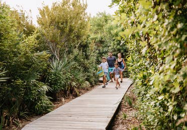 Family of four walking down walkway near Cape Canaveral Beach Resort in Florida.