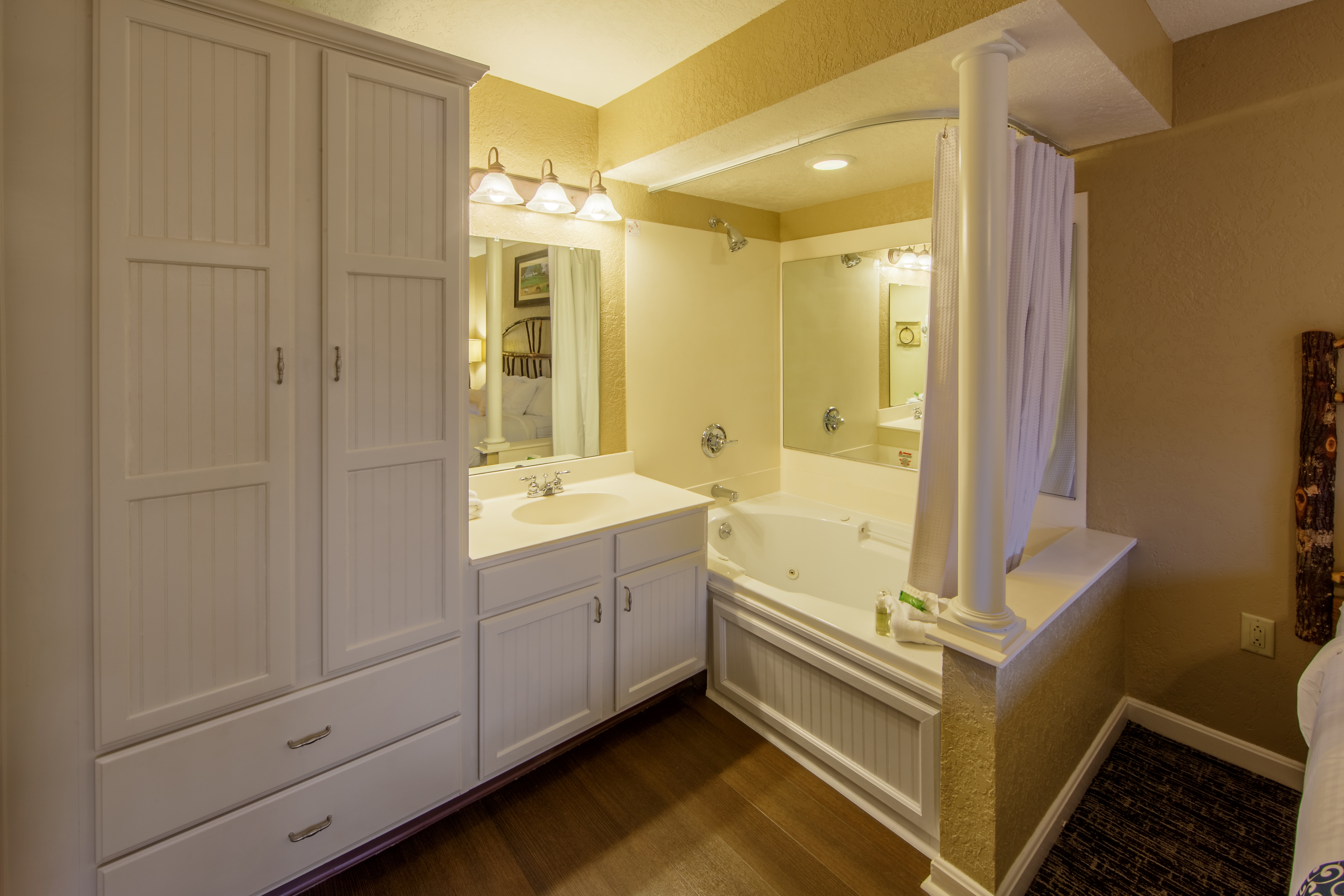 Bathroom with large storage cabinet, vanity, and large soaking tub in a two bedroom villa at Oak n' Spruce Resort in South Lee, Massachusetts