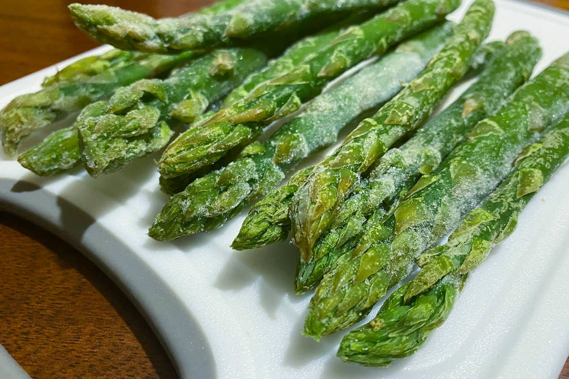 Frozen asparagus sits on a white plate.