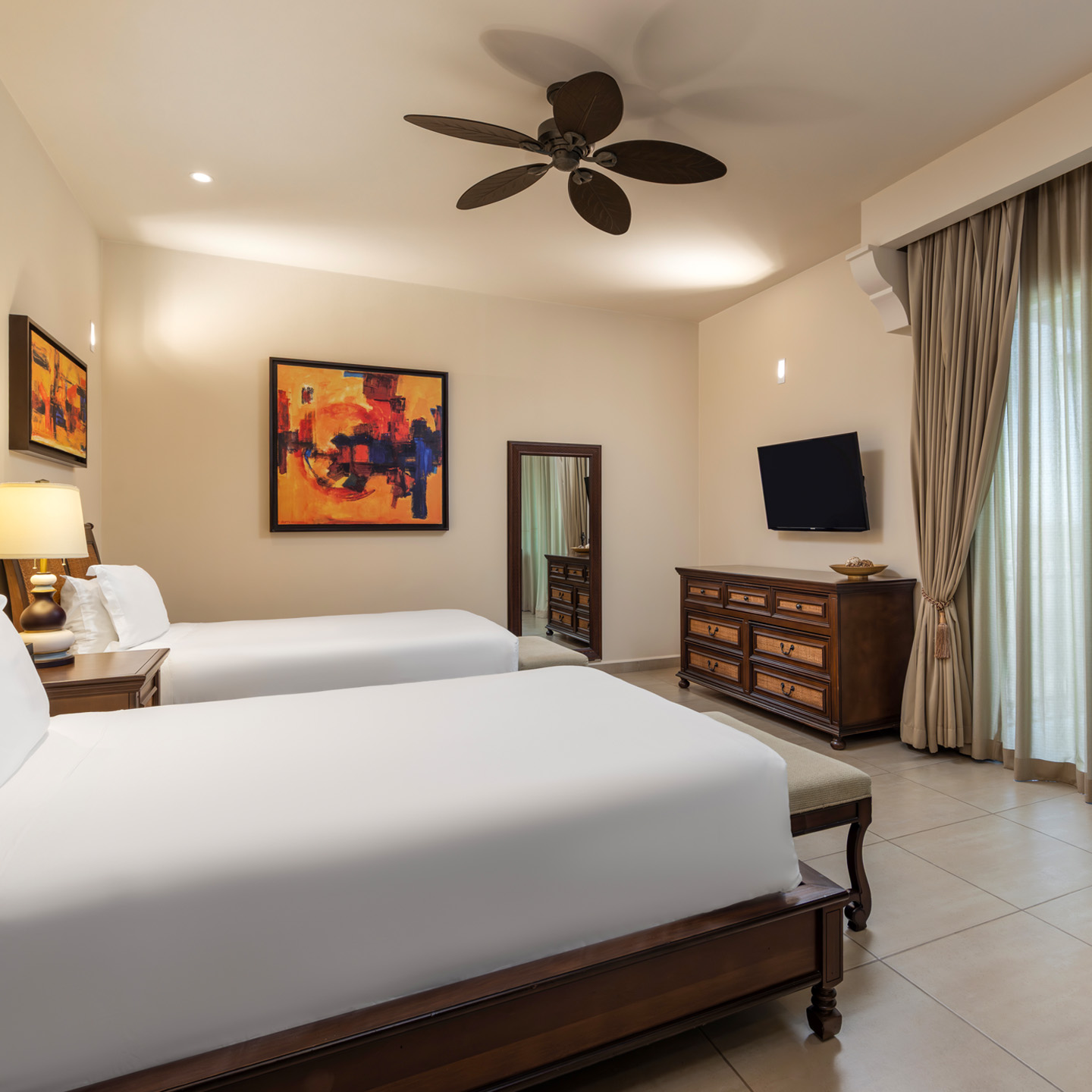 Suite bedroom with double beds, dresser, TV, and large window. 