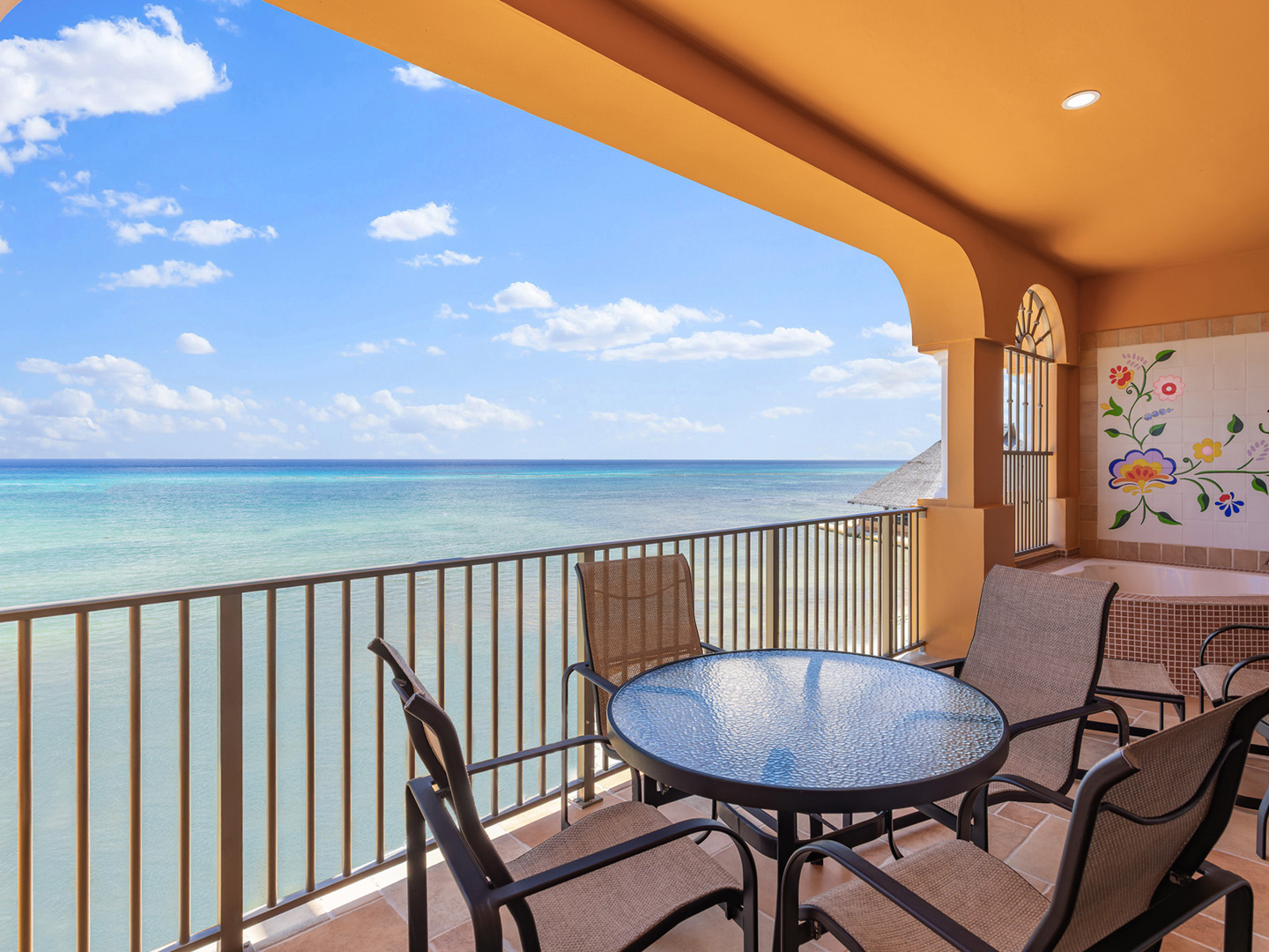 Oceanfront balcony with table, chairs, and soaking tub.
