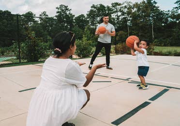 Family with two adults and small child playing basketball at Williamsburg Resort in Virginia.