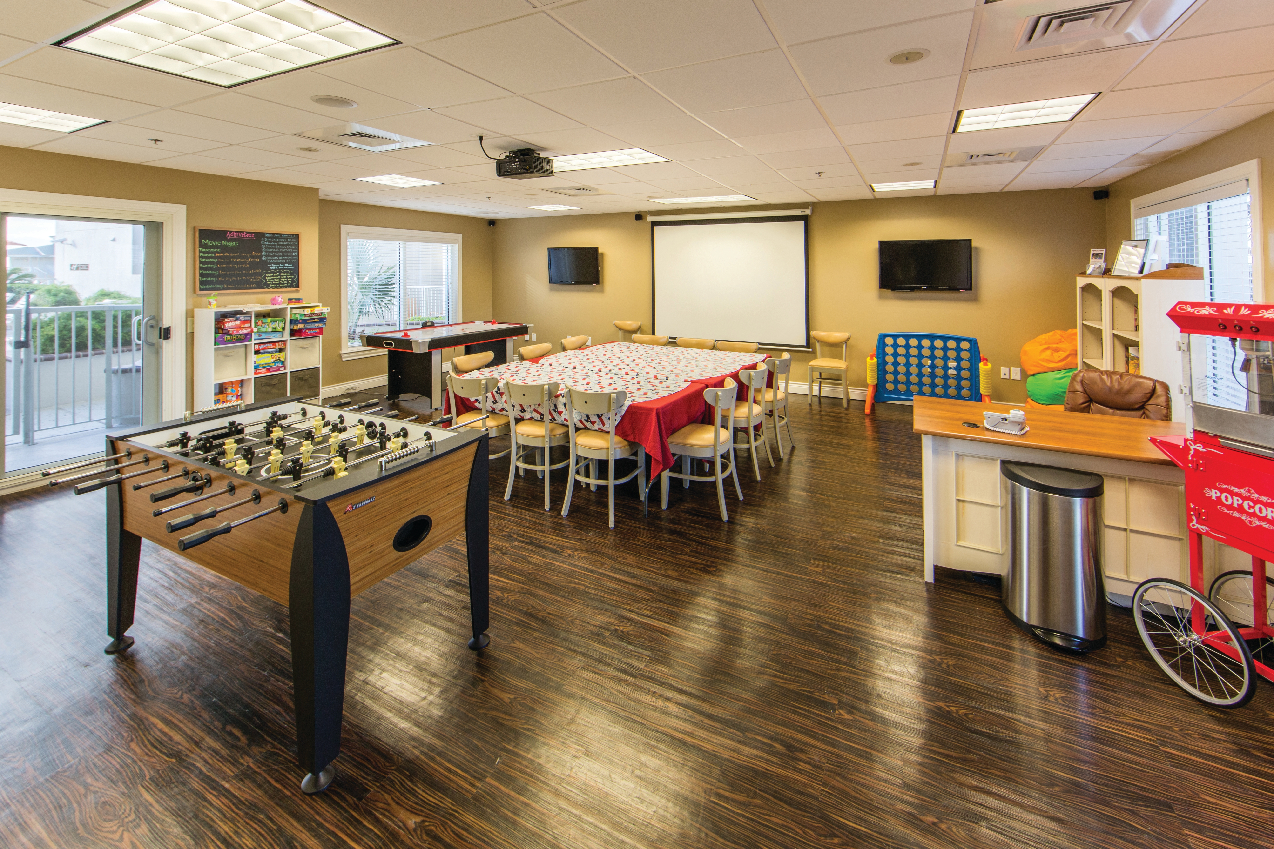 Game room with Foosball table, giant Connect 4, popcorn machine, and seating area in front of projector at Galveston Beach Resort.