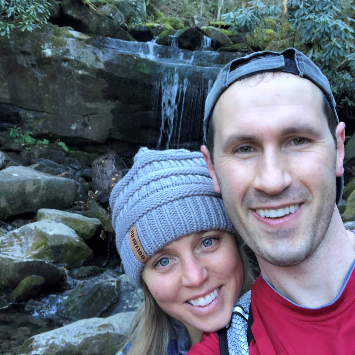 Tiffany (left) and her husband (right) pose in front of a waterfall in Gatlinburg, TN.