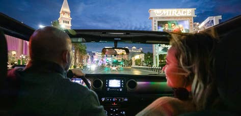 Couple driving down Las Vegas Strip while visiting Desert Club Resort in Nevada.