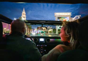 Couple driving down Las Vegas Strip while visiting Desert Club Resort in Nevada.