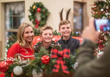 Author, Amanda Nall (left), pose on Santa's sleigh with her sons for a photograph surrounded by holiday decor.