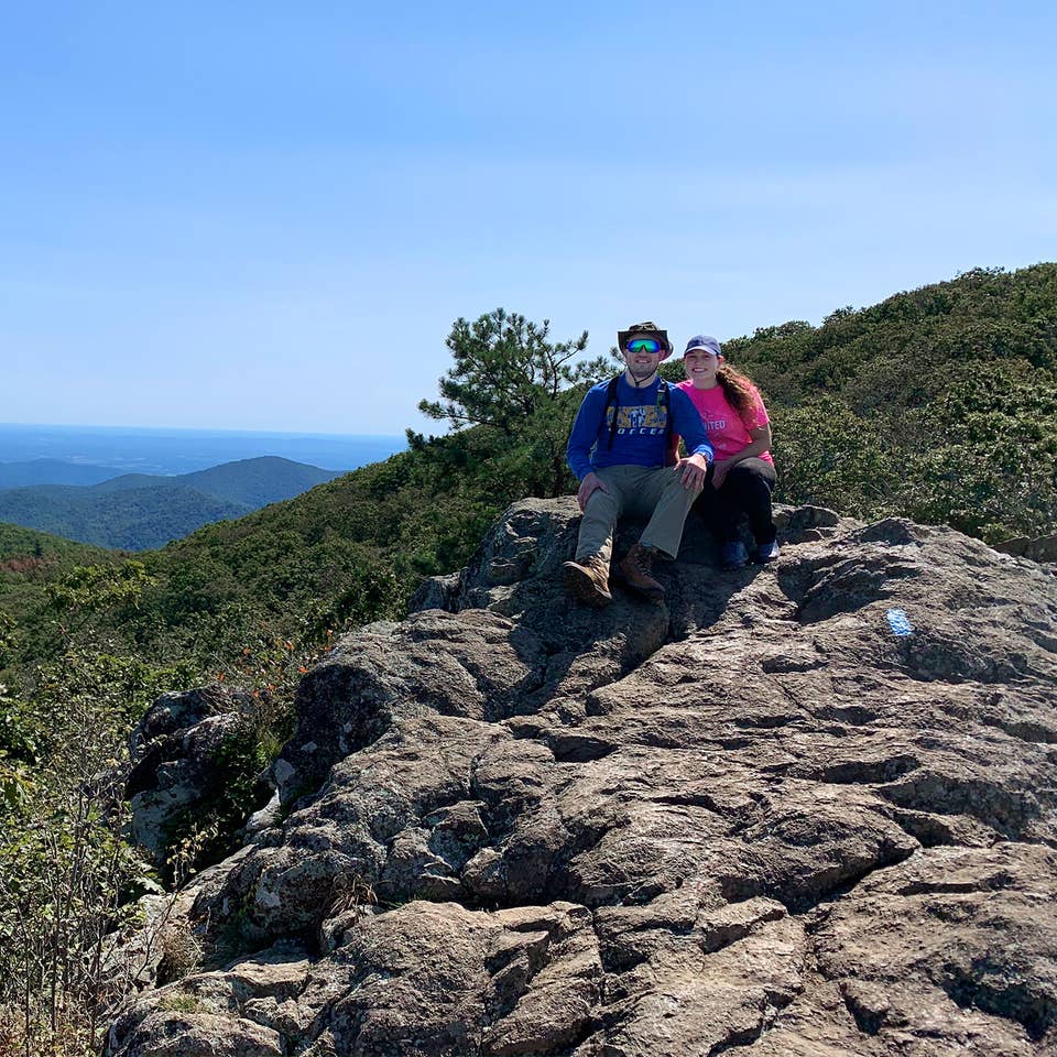 Featured Contributor, Ashley Fraboni (right) and Fiancé, Nicholas (left) sit atop a rock a Shenandoah National Park.