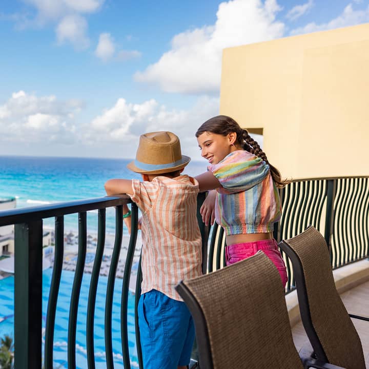 Kids on a balcony overlooking the pool and ocean at Royal Sands Resort.