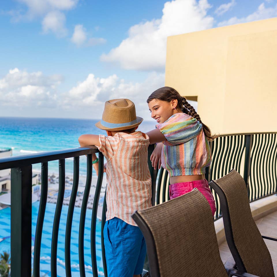 Kids on a balcony overlooking the pool and ocean at Royal Sands Resort.