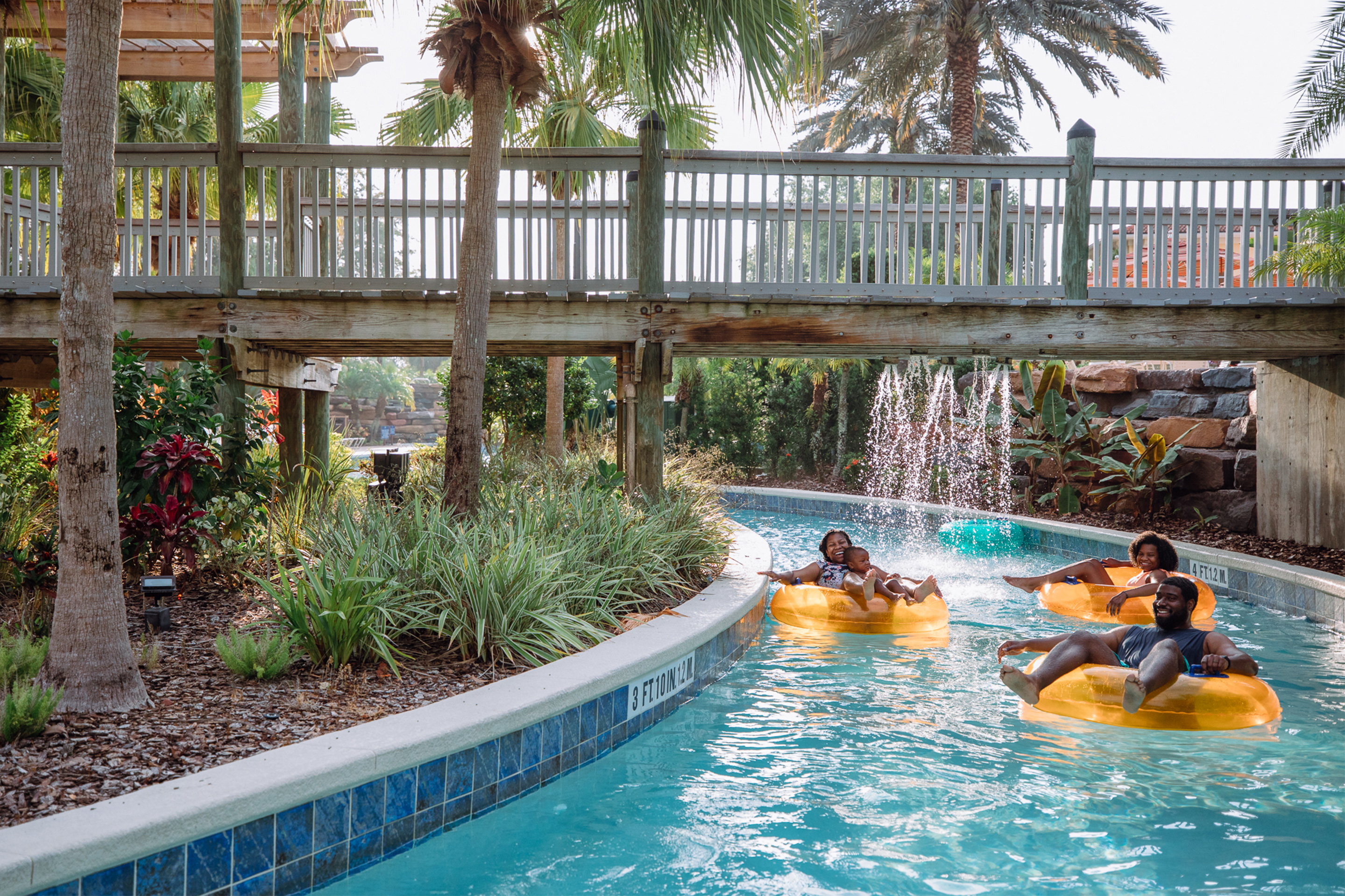 The Godfrey family sits on orange inner tubes in the lazy river in River Island at our Orange Lake resort located in Orlando, FL.