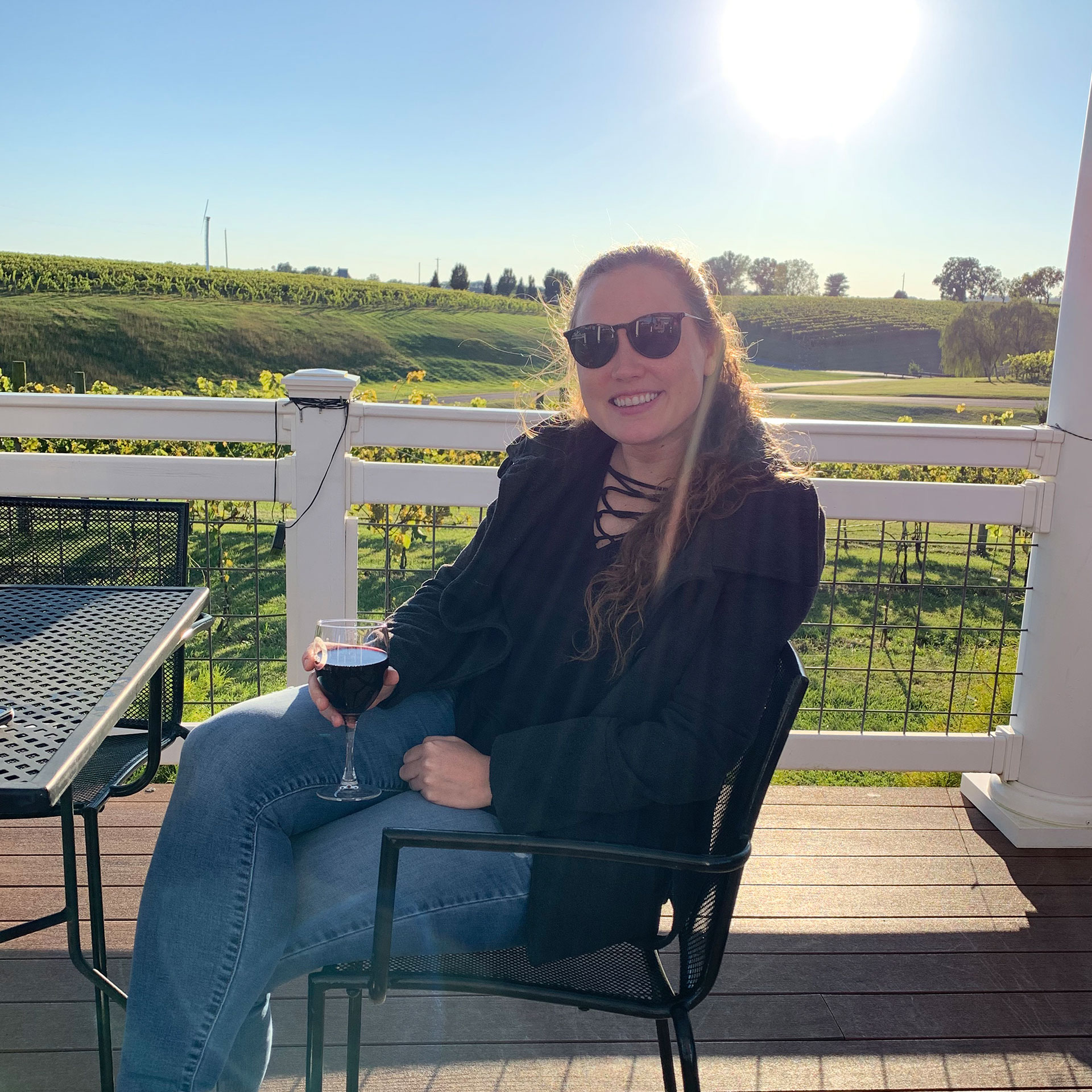 Featured Contributor, Ashley Fraboni holds a glass of wine outdoors at Cross Keys Winery in Harrisonburg, VA.