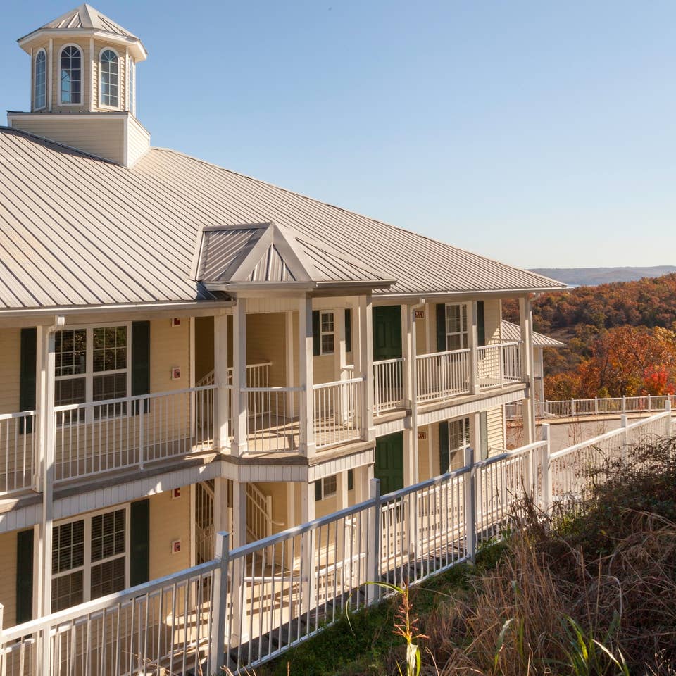 A property building that's painted off-white with a view of autumn foliage and mountains in the background at Ozark Mountain Resort in Missouri.