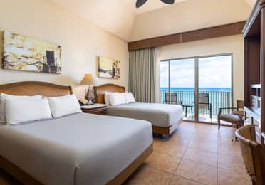 Oceanview bedroom with balcony and two comfortable beds.