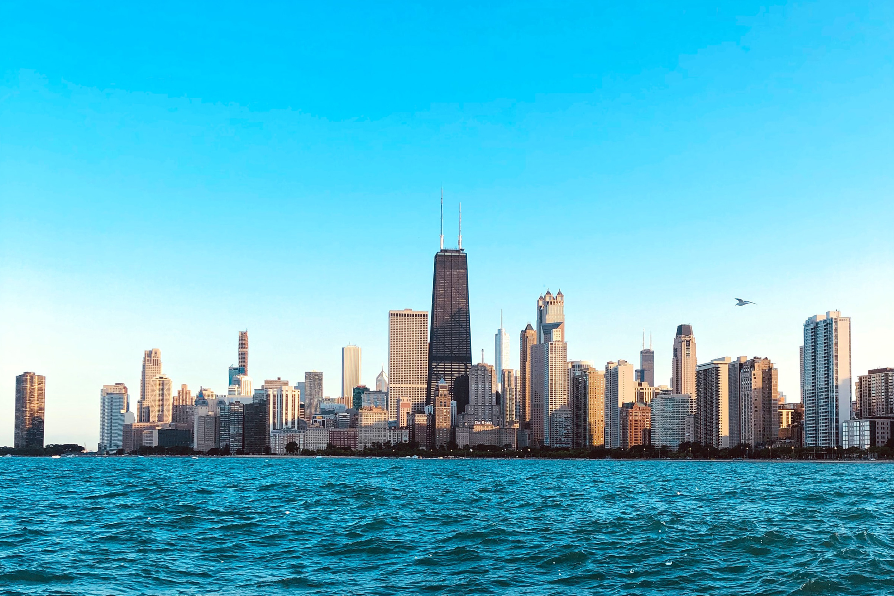 Chicago skyline surrounded by blue skies and blue waters of Lake Michigan.