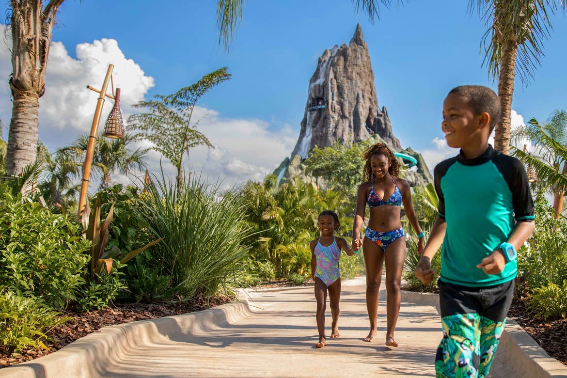 A son, daughter and mother wearing colorful aqua swimwear walk away from Volcano Bay located at Universal Orlando Resort.