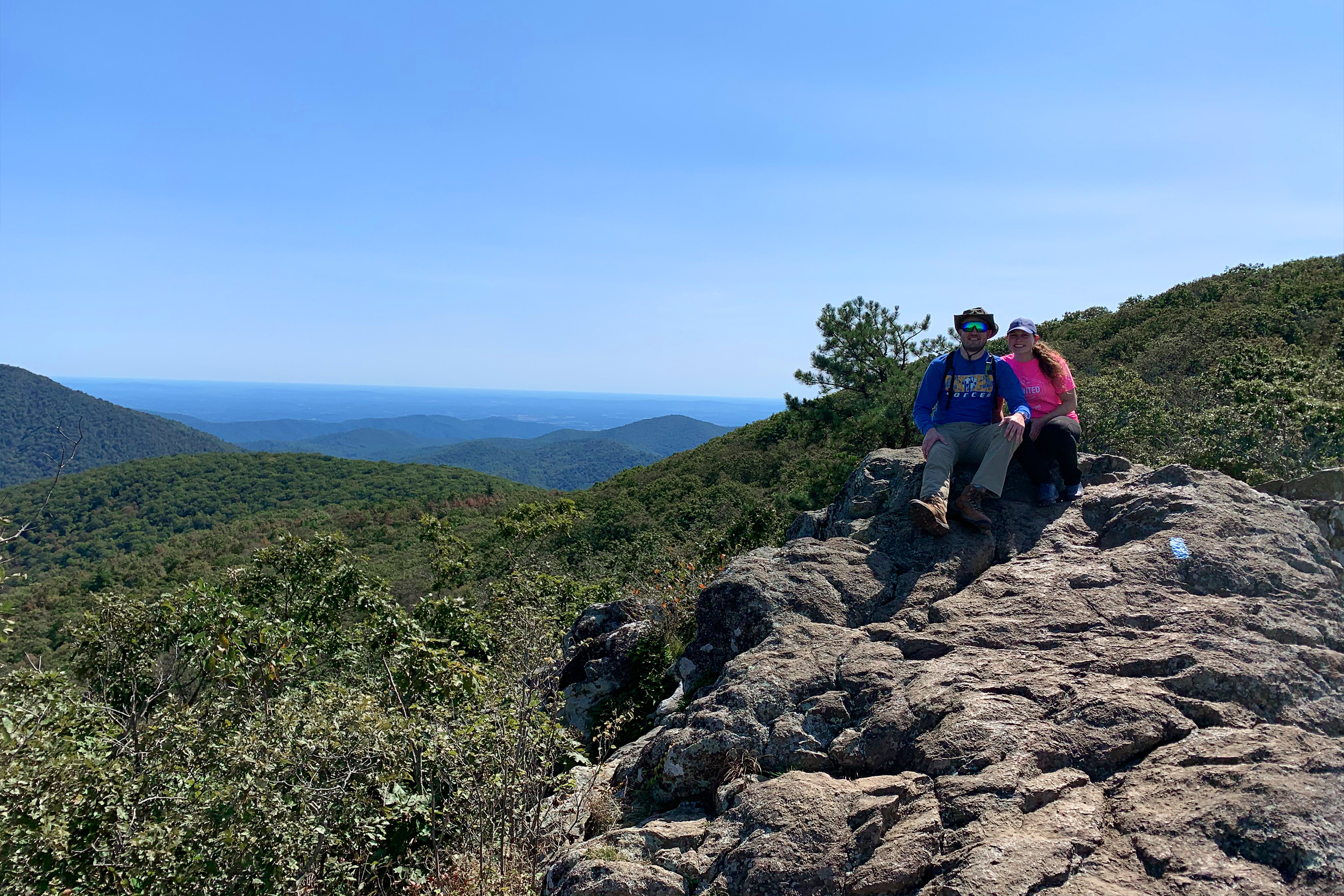 Featured Contributor, Ashley Fraboni (right) and Fiancé, Nicholas (left) sit atop a rock a Shenandoah National Park.