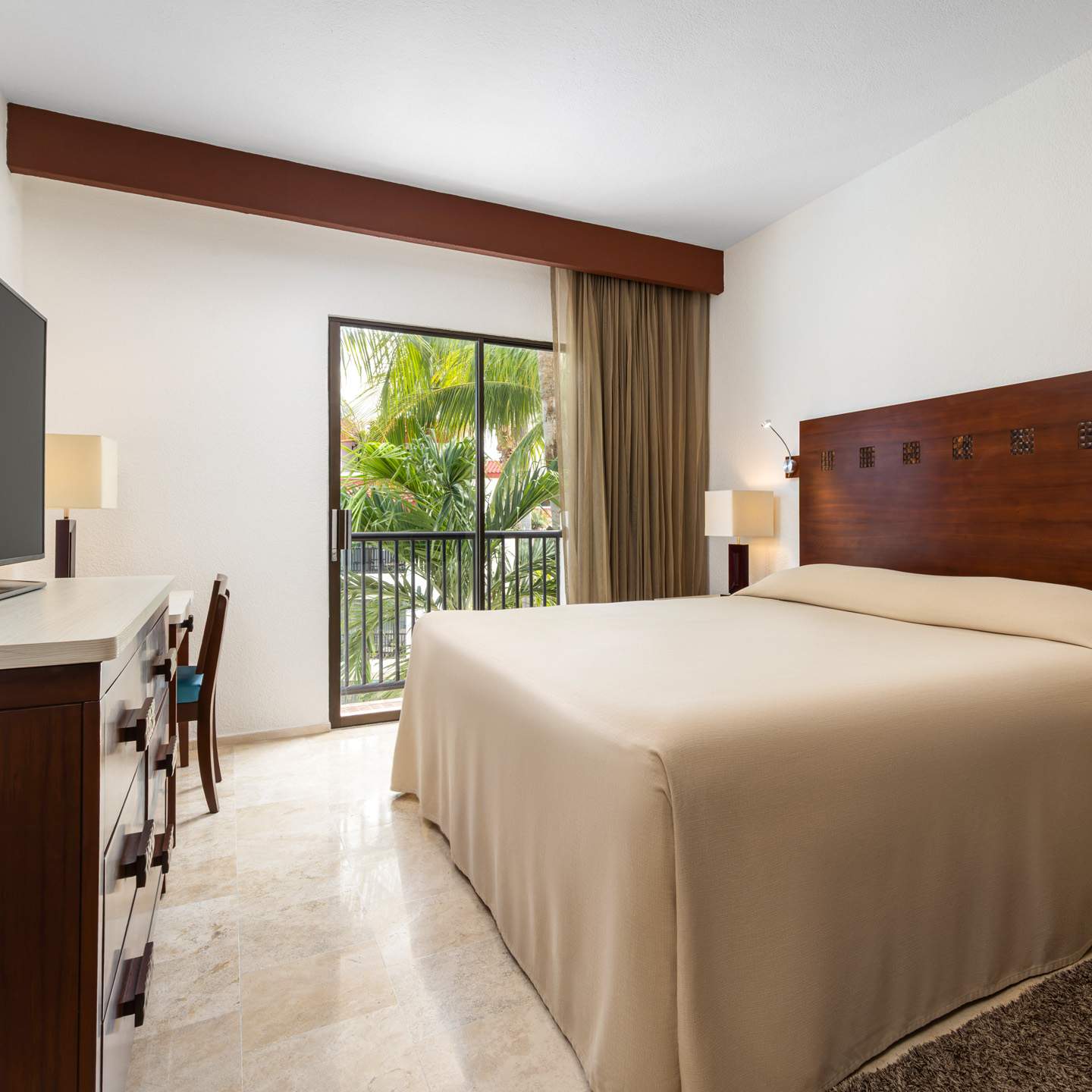Suite bedroom with king bed and balcony overlooking gardens.