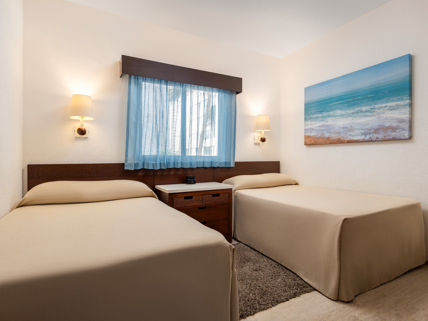 Modern bedroom with two twin beds, a window, and coastal artwork.