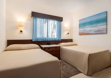 Modern bedroom with two twin beds, a window, and coastal artwork.