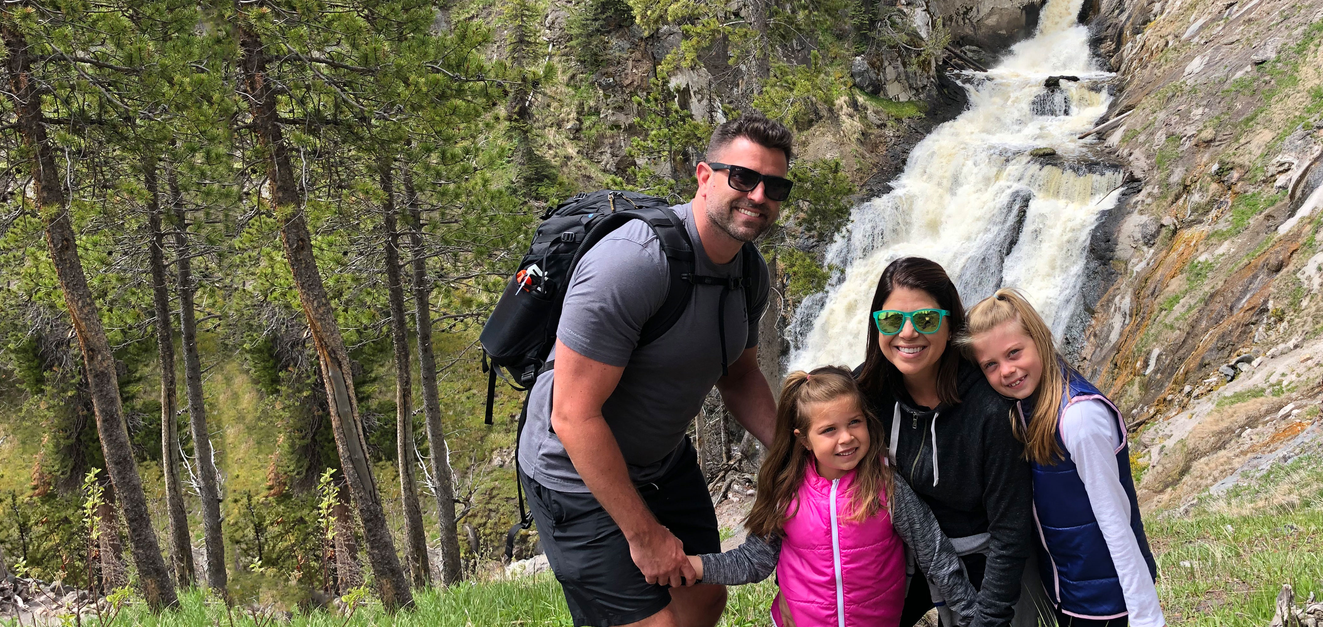 Author, Chris Johnston (middle-right), stands in front of the Mystic Falls at Yellowstone National Park with her husband, Josh (far-left), and daughters, Kyndall (far-right), and Kyler (middle-left).