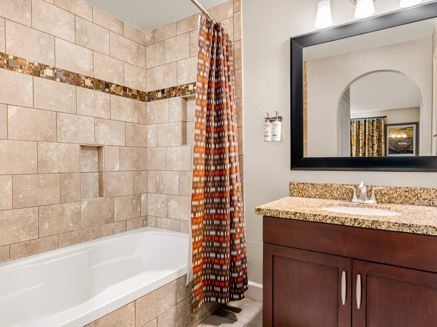 Elegant bath with granite vanity and modern tiled shower combo.
