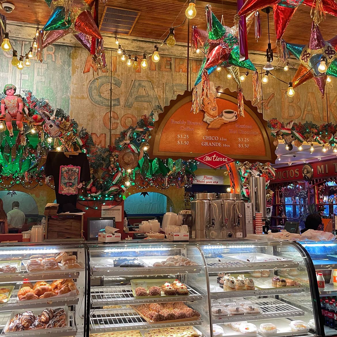 A bakery interior clad with string lights, piñatas and rustic signage surrounds pastry displays. 