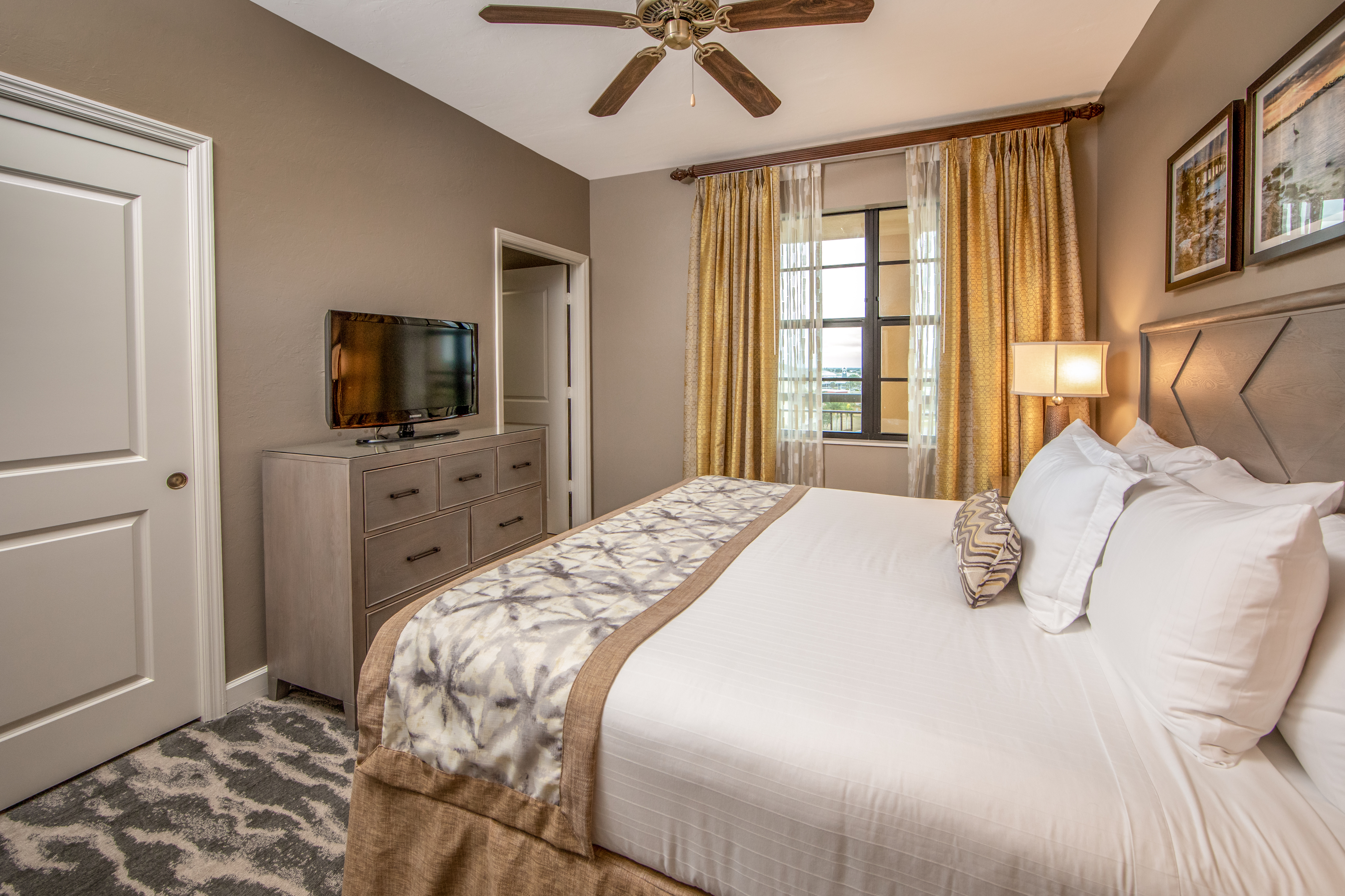 Bedroom with king bed, flat screen TV, and large window in a three-bedroom villa at Sunset Cove Resort in Marco Island, Florida