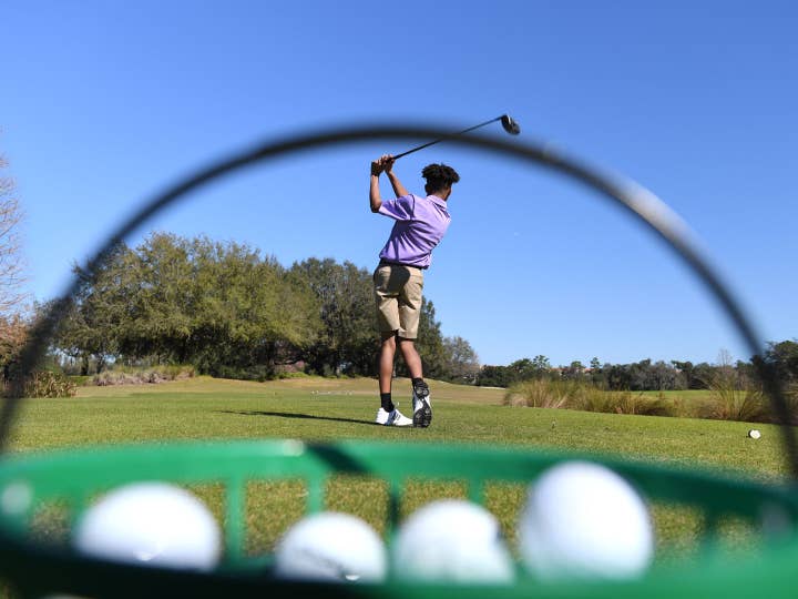 Shot of a kid swinging a golf club through a basket of golf balls at Orange Lake Resort in Orlando, FL.